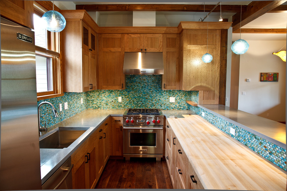 Modern inredning av ett u-kök, med skåp i shakerstil, rostfria vitvaror, bänkskiva i betong, en enkel diskho, skåp i mellenmörkt trä, flerfärgad stänkskydd och stänkskydd i mosaik