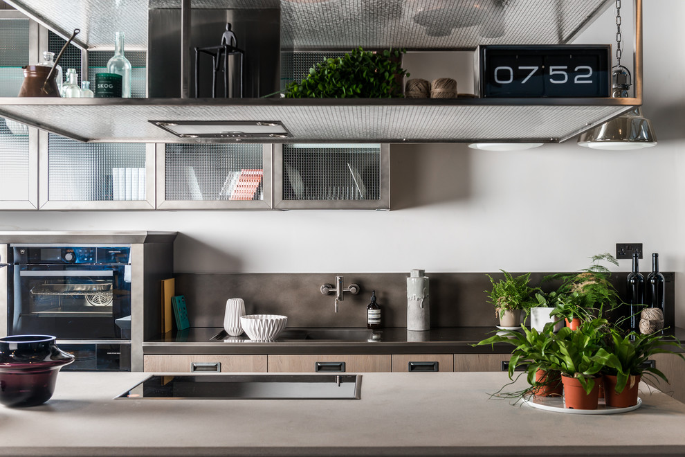 Idee per una grande cucina abitabile contemporanea con lavello integrato, ante di vetro, top in superficie solida, paraspruzzi grigio, penisola e ante in legno chiaro