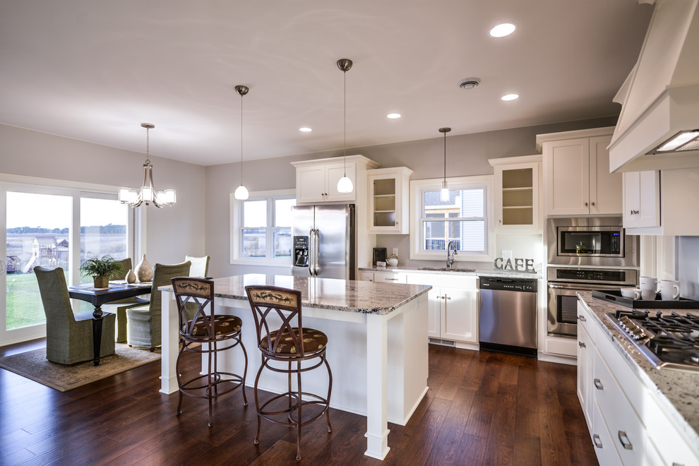 Mid-sized transitional l-shaped dark wood floor eat-in kitchen photo in Minneapolis with a double-bowl sink, flat-panel cabinets, white cabinets, granite countertops, gray backsplash, stainless steel appliances and subway tile backsplash