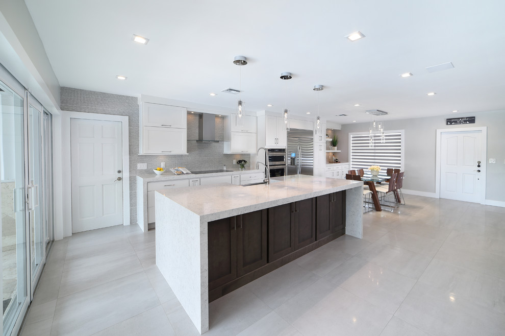 Large minimalist single-wall open concept kitchen photo in Miami with shaker cabinets, white cabinets, quartz countertops, gray backsplash, porcelain backsplash, stainless steel appliances and an island
