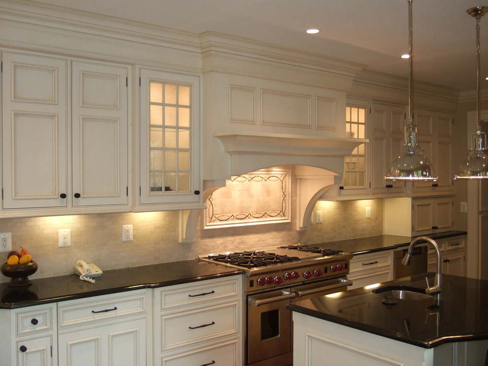 Ejemplo de cocina clásica con armarios con rebordes decorativos, electrodomésticos de acero inoxidable y puertas de armario blancas