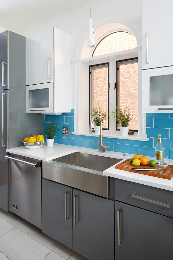 Foto de cocina de tamaño medio con armarios con paneles lisos, puertas de armario blancas, salpicadero azul, salpicadero de azulejos tipo metro, electrodomésticos de acero inoxidable y suelo gris