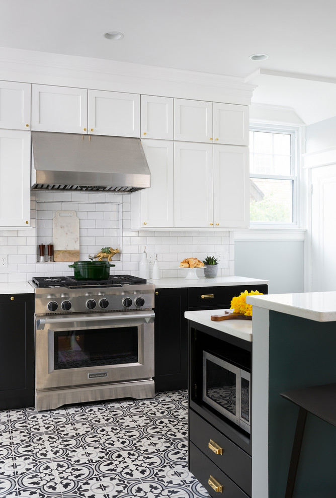 Foto de cocina comedor clásica renovada de tamaño medio con puertas de armario negras, salpicadero blanco, salpicadero de azulejos tipo metro, electrodomésticos de acero inoxidable y suelo negro