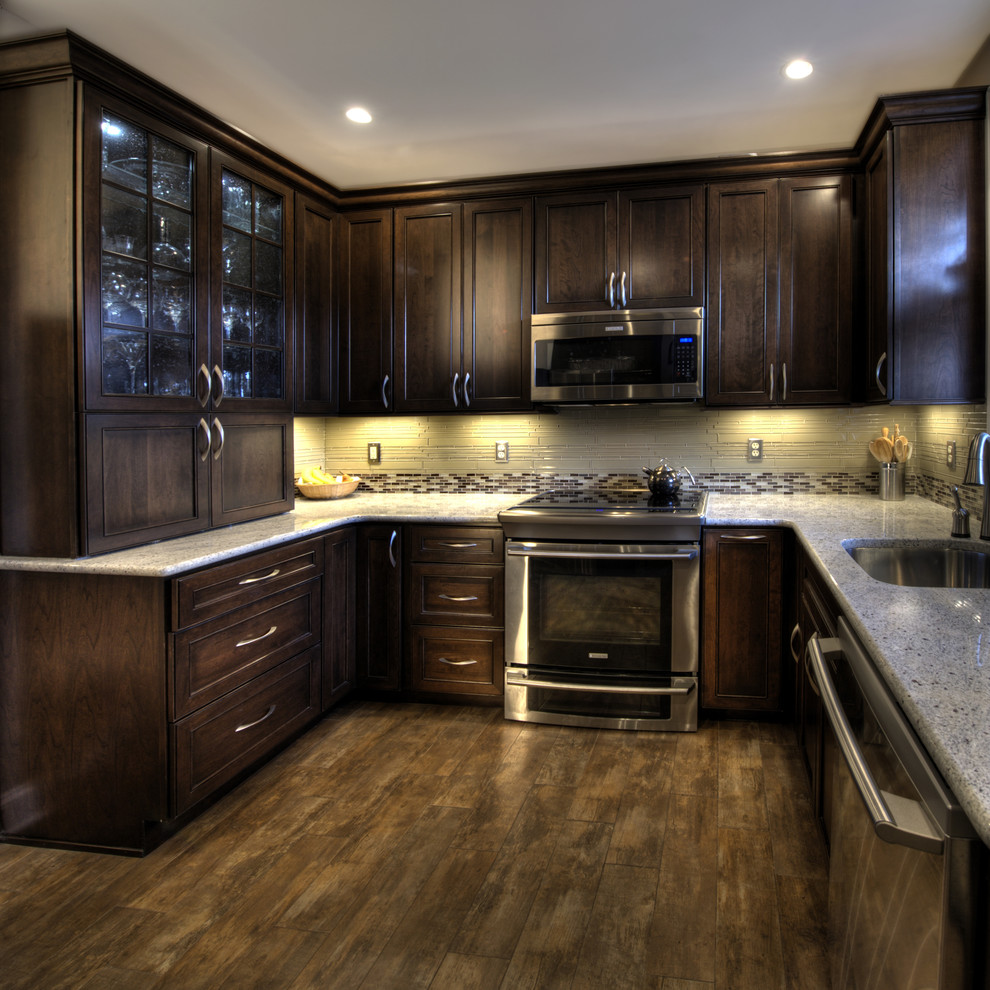 Example of a mid-sized classic u-shaped ceramic tile enclosed kitchen design in DC Metro with glass tile backsplash, stainless steel appliances, an undermount sink, granite countertops, recessed-panel cabinets, dark wood cabinets, multicolored backsplash and no island