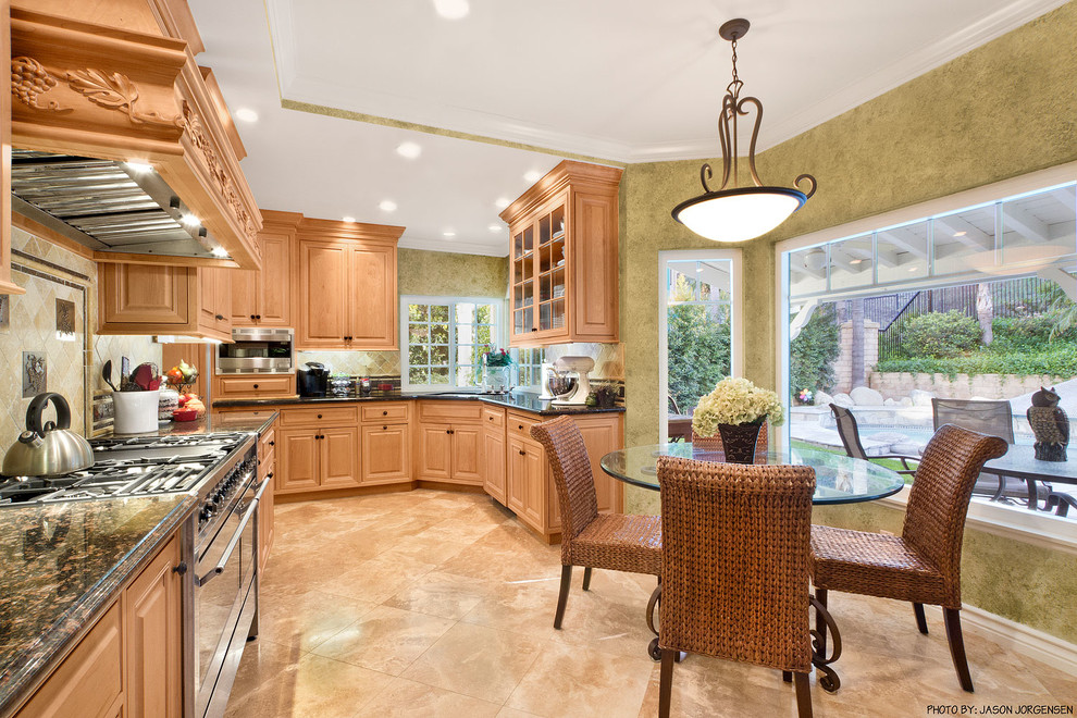 Example of a large classic l-shaped limestone floor eat-in kitchen design in Los Angeles with an undermount sink, raised-panel cabinets, light wood cabinets, granite countertops, beige backsplash, stone tile backsplash, stainless steel appliances and no island