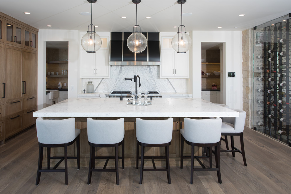 Inspiration for a coastal medium tone wood floor kitchen remodel in Orange County with shaker cabinets, white cabinets, white backsplash, stainless steel appliances and an island