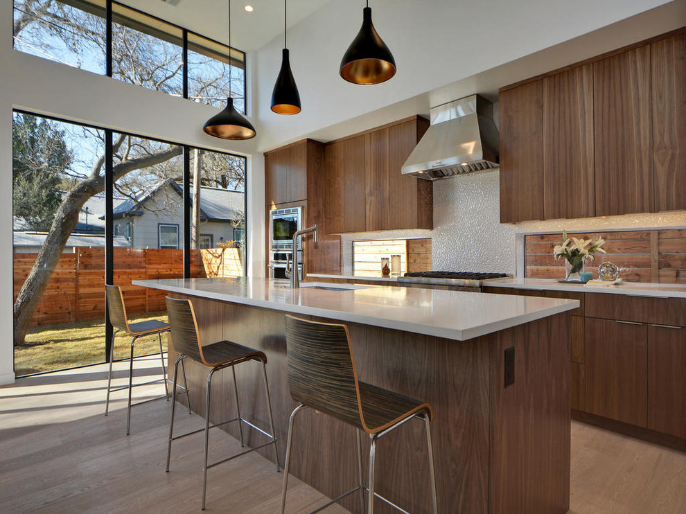 Cette image montre une cuisine minimaliste en bois brun avec un évier encastré, un placard à porte plane, une crédence beige, un électroménager en acier inoxydable, un sol en bois brun et îlot.