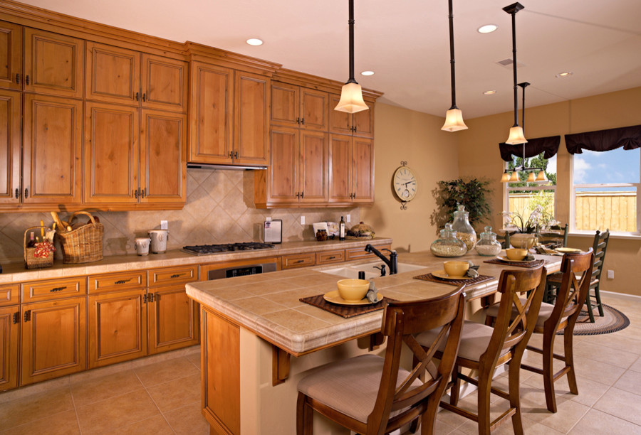 Example of a cottage single-wall open concept kitchen design in Other with a double-bowl sink, medium tone wood cabinets, tile countertops, beige backsplash, ceramic backsplash and stainless steel appliances