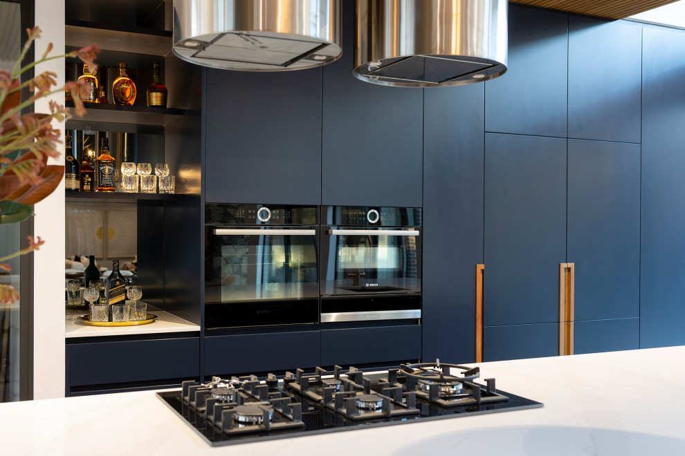 Foto på ett stort funkis vit kök, med en undermonterad diskho, blå skåp, bänkskiva i kvarts, svarta vitvaror, klinkergolv i porslin, en köksö och grått golv