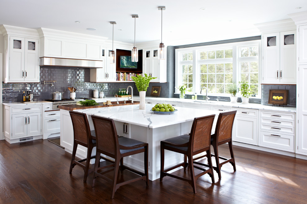 Example of a classic l-shaped dark wood floor kitchen design in New York with shaker cabinets, white cabinets, gray backsplash, ceramic backsplash and an island