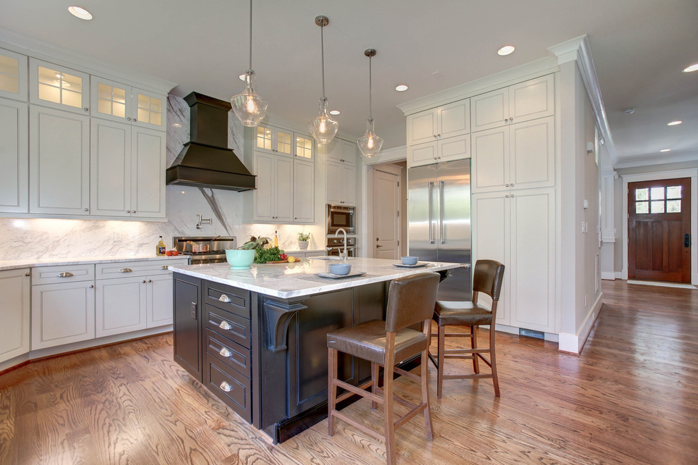 Large transitional u-shaped medium tone wood floor eat-in kitchen photo in DC Metro with a farmhouse sink, raised-panel cabinets, white cabinets, marble countertops, white backsplash, stone slab backsplash, stainless steel appliances and an island