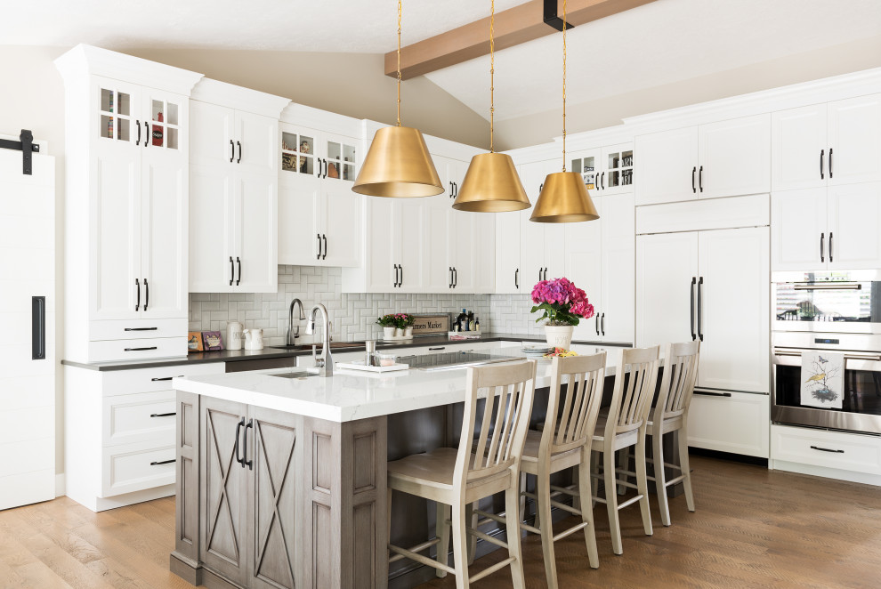 Idéer för ett modernt vit l-kök, med en undermonterad diskho, luckor med infälld panel, vita skåp, vitt stänkskydd, rostfria vitvaror, mellanmörkt trägolv, en köksö och brunt golv