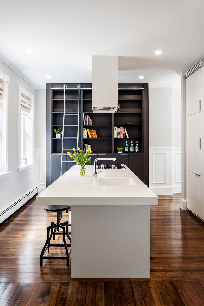 Small modern kitchen/diner in Boston with an integrated sink, flat-panel cabinets, white cabinets, composite countertops, integrated appliances, dark hardwood flooring and an island.