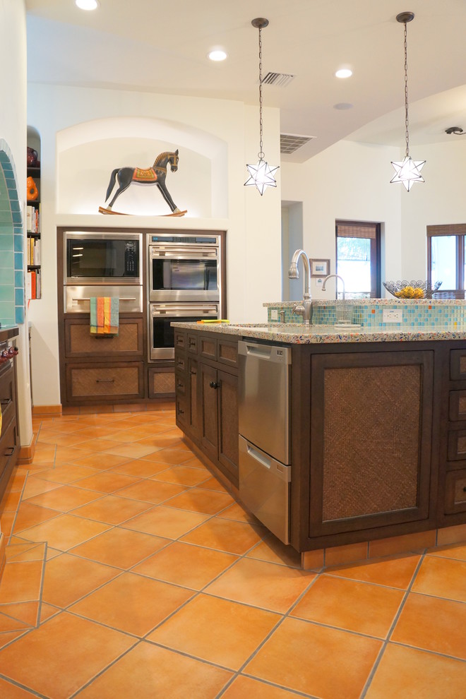 Bild på ett stort medelhavsstil kök, med en undermonterad diskho, luckor med lamellpanel, bruna skåp, bänkskiva i återvunnet glas, blått stänkskydd, stänkskydd i mosaik, rostfria vitvaror, klinkergolv i terrakotta, en köksö och orange golv