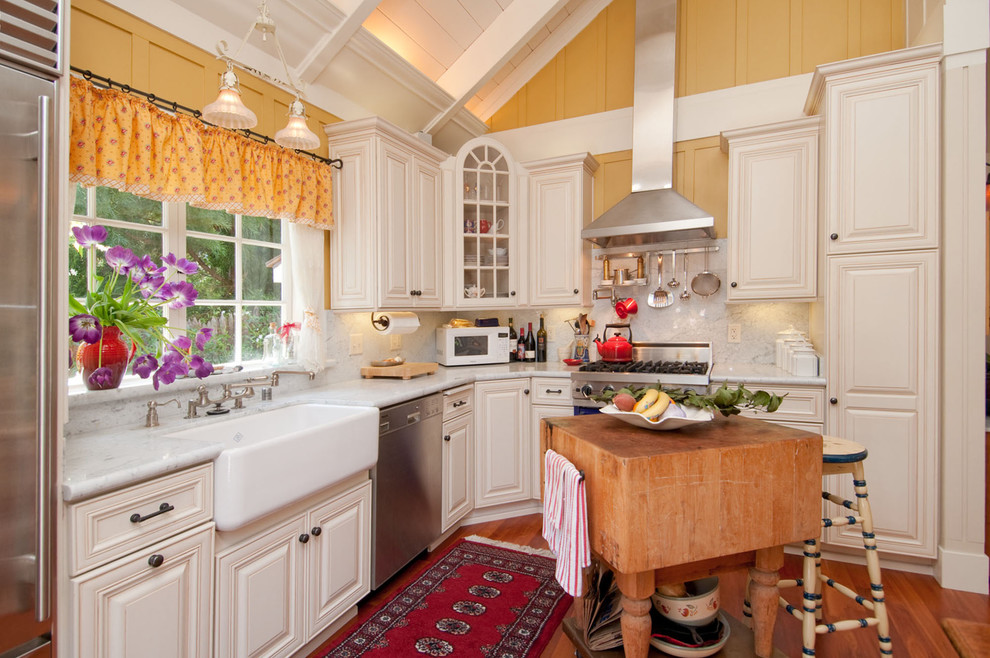 Elegant l-shaped kitchen photo in Seattle with a farmhouse sink, white cabinets, white backsplash, stone slab backsplash and colored appliances