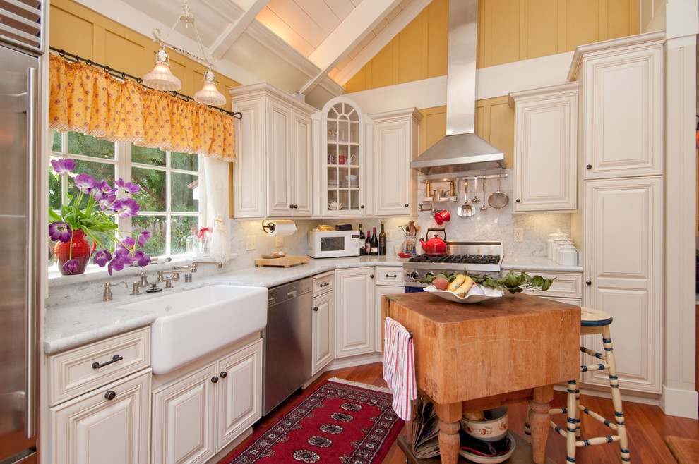 Photo of a classic l-shaped kitchen in Seattle with a belfast sink, white cabinets, white splashback, stone slab splashback and coloured appliances.