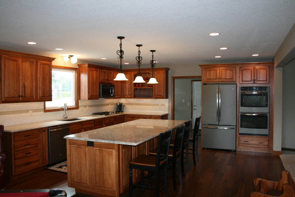 Exempel på ett mellanstort klassiskt kök, med en dubbel diskho, luckor med upphöjd panel, skåp i mörkt trä, granitbänkskiva, beige stänkskydd, stänkskydd i keramik, rostfria vitvaror, mörkt trägolv och en köksö