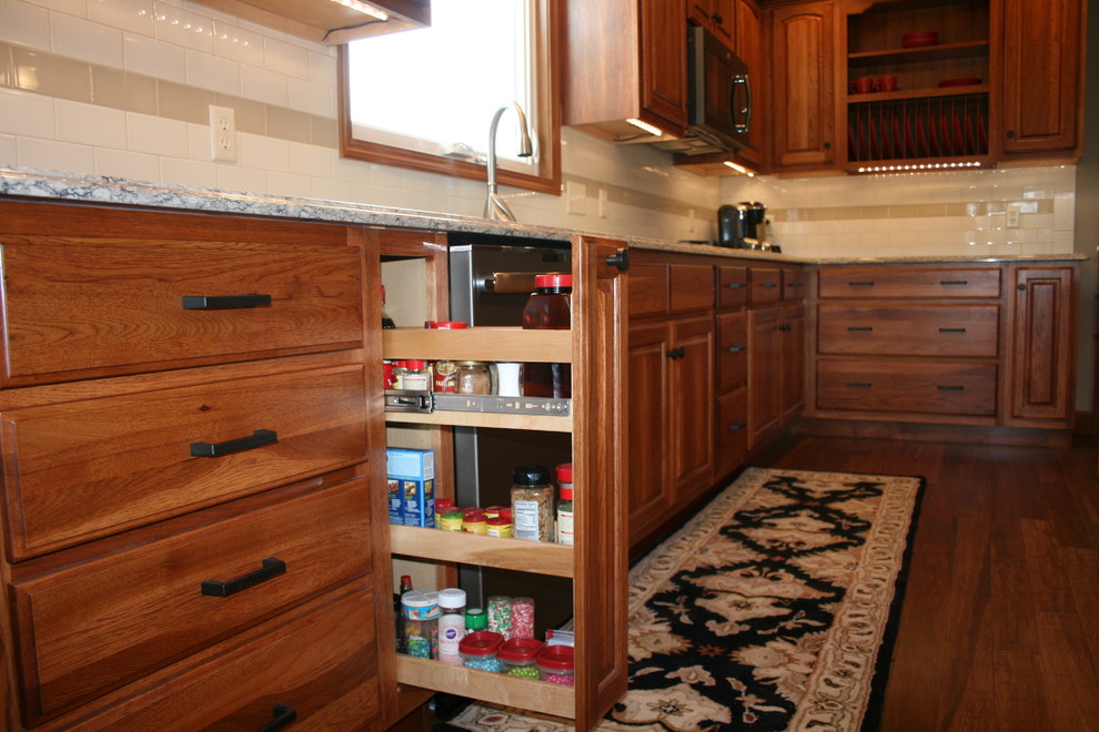 Inredning av ett klassiskt mellanstort kök, med en dubbel diskho, luckor med upphöjd panel, skåp i mörkt trä, granitbänkskiva, beige stänkskydd, stänkskydd i keramik, rostfria vitvaror, mörkt trägolv, en köksö och brunt golv