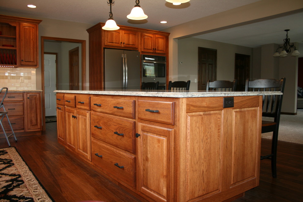 Klassisk inredning av ett mellanstort kök, med en dubbel diskho, luckor med upphöjd panel, skåp i mörkt trä, granitbänkskiva, beige stänkskydd, stänkskydd i keramik, rostfria vitvaror, mörkt trägolv och en köksö