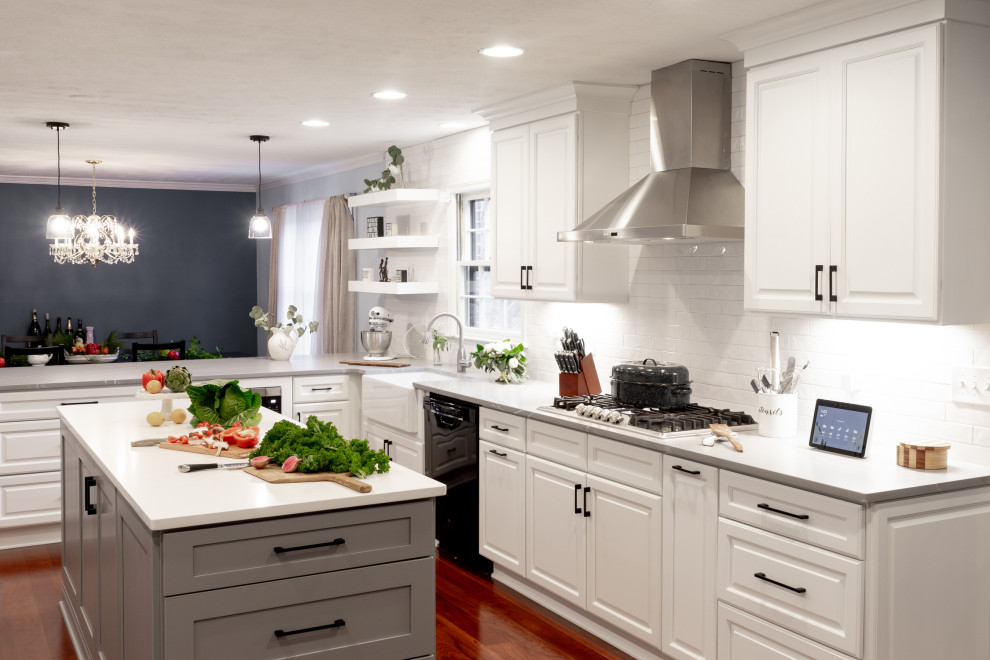 Example of a mid-sized farmhouse l-shaped medium tone wood floor and brown floor eat-in kitchen design in Atlanta with a farmhouse sink, raised-panel cabinets, white cabinets, quartz countertops, white backsplash, subway tile backsplash, stainless steel appliances, a peninsula and gray countertops