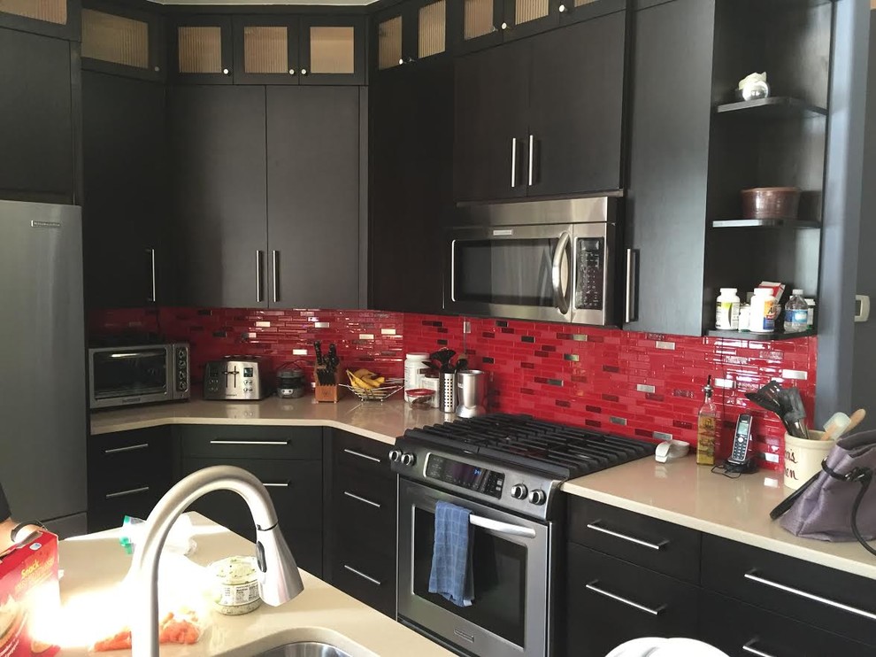 Ejemplo de cocina contemporánea de tamaño medio con puertas de armario negras, salpicadero rojo, salpicadero de azulejos de vidrio, electrodomésticos de acero inoxidable y una isla