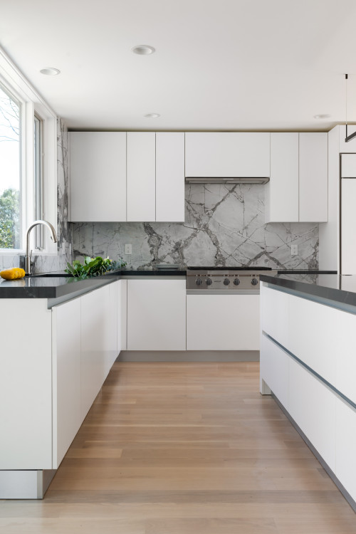 Gray and White Harmony: Gray Marble Backsplash Complements White Flat-Panel Cabinets and a Black Countertop