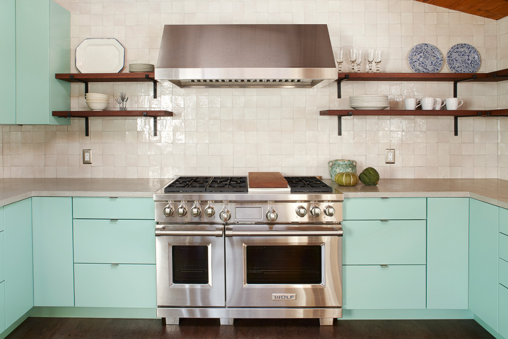 ボストンにあるミッドセンチュリースタイルのおしゃれなコの字型キッチン (フラットパネル扉のキャビネット、青いキャビネット、ベージュキッチンパネル、シルバーの調理設備、濃色無垢フローリング、グレーのキッチンカウンター) の写真