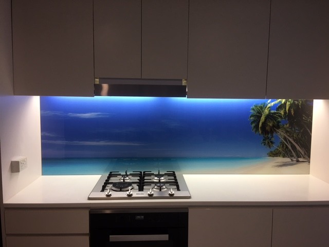 Idée de décoration pour une cuisine américaine linéaire marine de taille moyenne avec une crédence bleue, une crédence en feuille de verre et îlot.