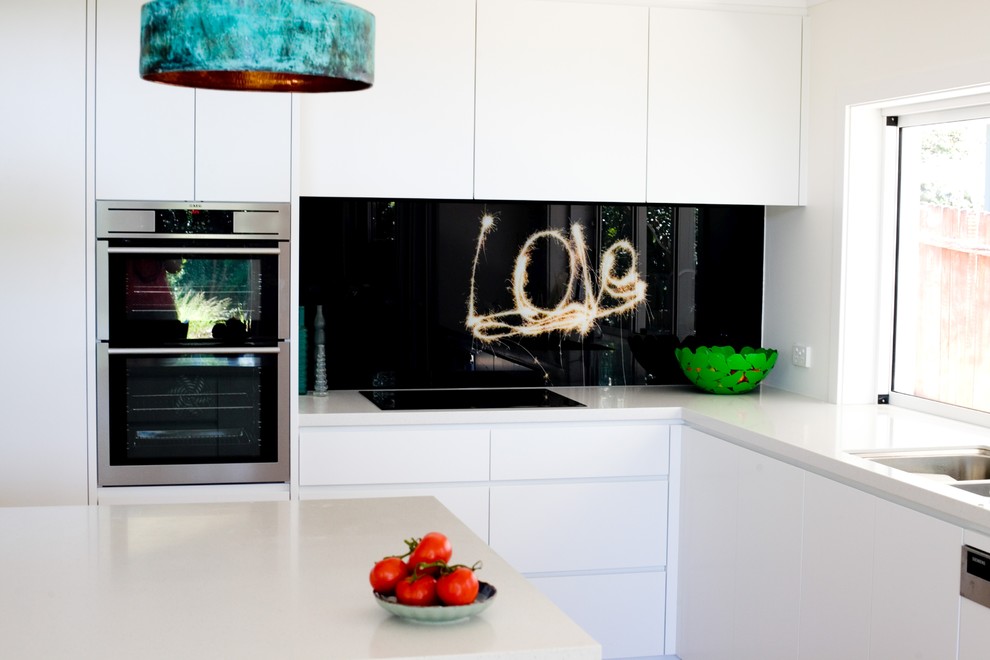 Exempel på ett litet modernt linjärt kök och matrum, med en undermonterad diskho, svart stänkskydd, glaspanel som stänkskydd, rostfria vitvaror och en köksö
