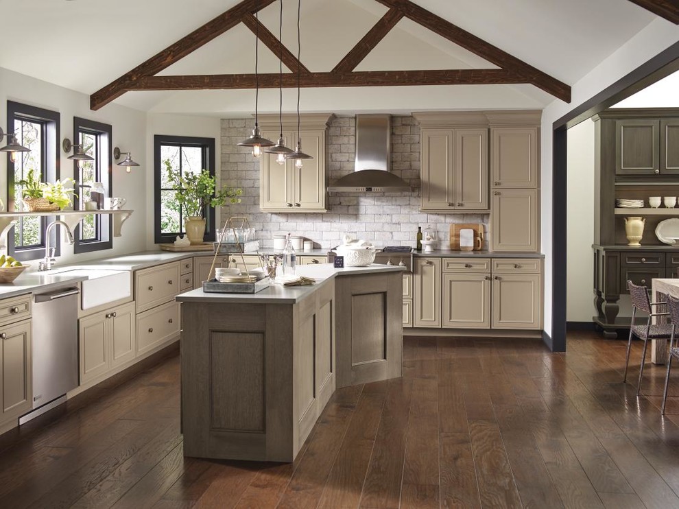 Inspiration for a large transitional l-shaped brown floor and medium tone wood floor eat-in kitchen remodel in Other with beige cabinets, an island, a farmhouse sink, recessed-panel cabinets, brick backsplash, stainless steel appliances and gray countertops