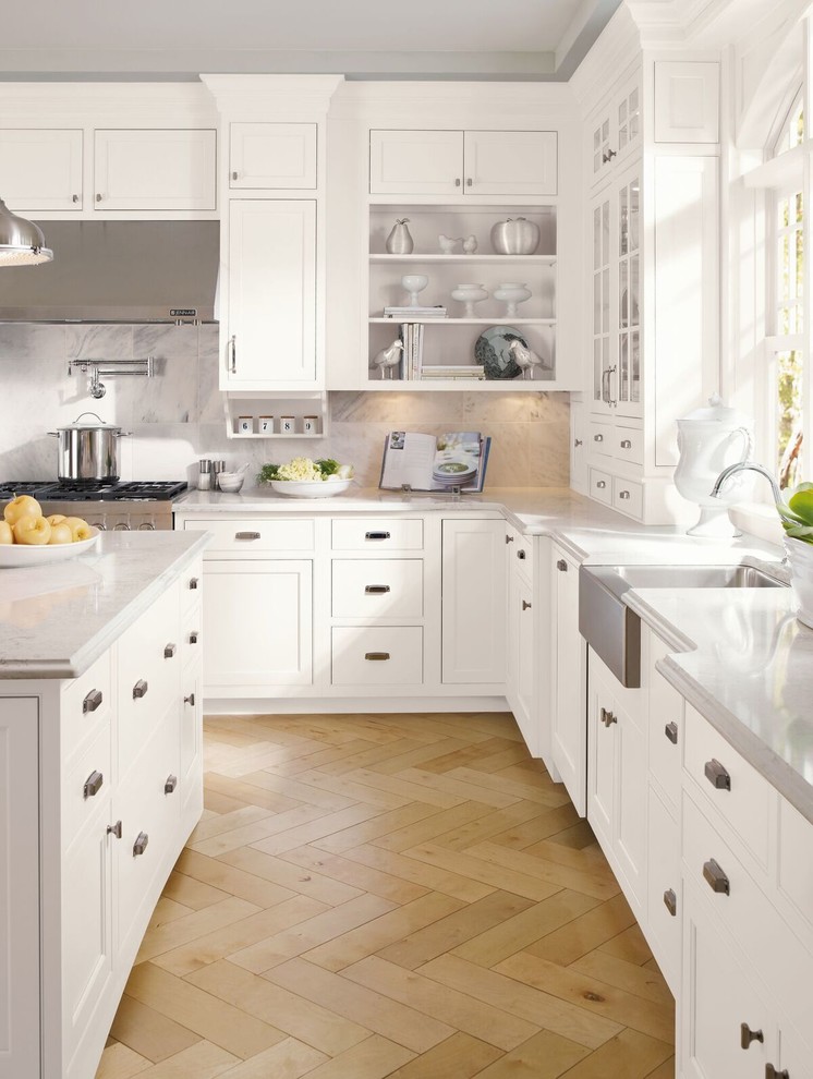 Inredning av ett klassiskt avskilt, mellanstort l-kök, med en rustik diskho, luckor med infälld panel, vita skåp, grått stänkskydd, rostfria vitvaror, ljust trägolv, beiget golv, bänkskiva i kvarts, stänkskydd i marmor och en köksö