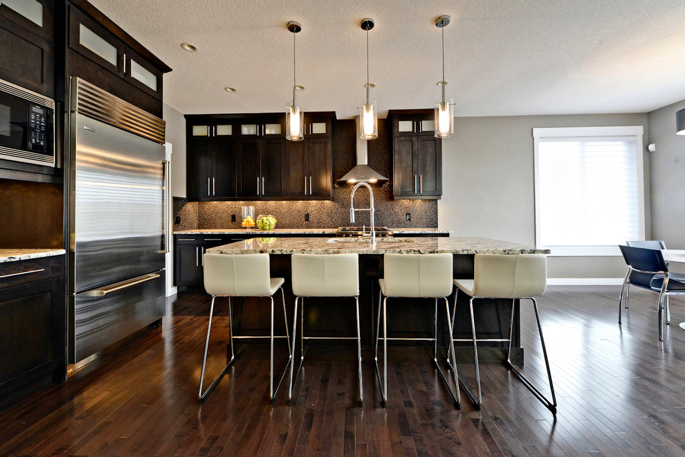 Eat-in kitchen - large contemporary l-shaped dark wood floor eat-in kitchen idea in Calgary with an undermount sink, shaker cabinets, dark wood cabinets, granite countertops, brown backsplash, mosaic tile backsplash, stainless steel appliances and an island