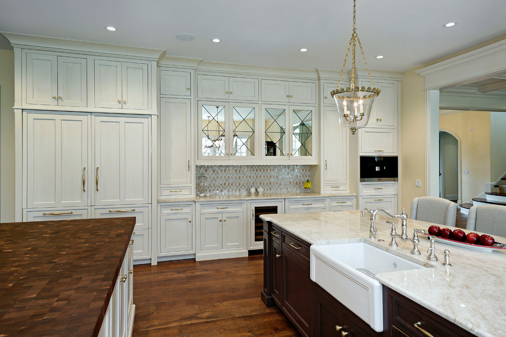 Example of a large classic medium tone wood floor open concept kitchen design in Chicago with recessed-panel cabinets and two islands
