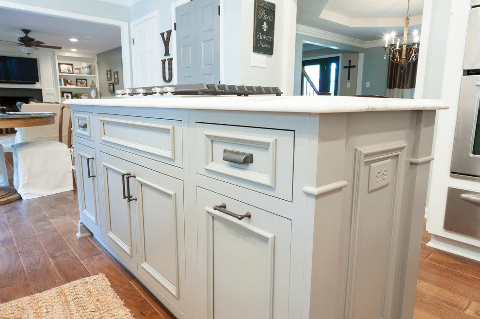 Inspiration for a mid-sized transitional l-shaped dark wood floor eat-in kitchen remodel in Indianapolis with a single-bowl sink, raised-panel cabinets, white cabinets, marble countertops, gray backsplash, stainless steel appliances and an island