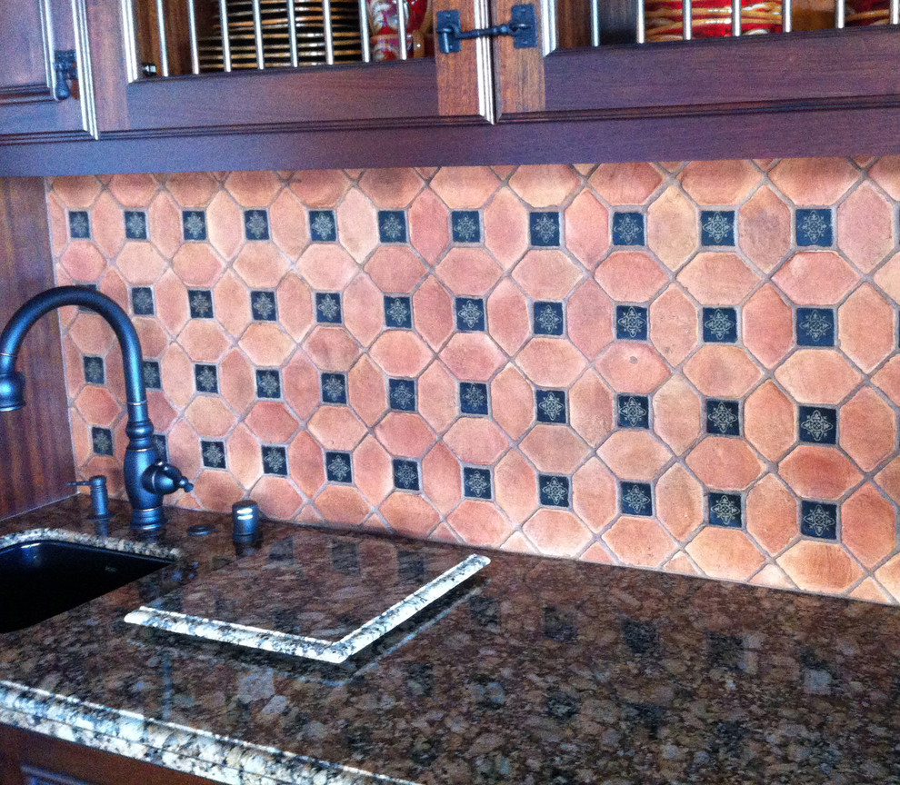 Bild på ett stort medelhavsstil kök, med en undermonterad diskho, luckor med upphöjd panel, skåp i mellenmörkt trä, granitbänkskiva, beige stänkskydd, stänkskydd i stenkakel, rostfria vitvaror, klinkergolv i terrakotta och en köksö