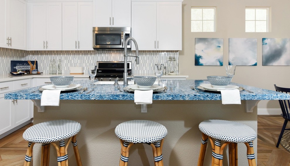 Medium sized nautical l-shaped kitchen/diner in Sacramento with a belfast sink, shaker cabinets, white cabinets, engineered stone countertops, multi-coloured splashback, porcelain splashback, stainless steel appliances, porcelain flooring and an island.