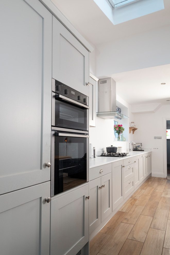 Design ideas for a medium sized classic single-wall open plan kitchen in Cardiff with a submerged sink, shaker cabinets, blue cabinets, wood worktops, stainless steel appliances, porcelain flooring, an island and brown floors.