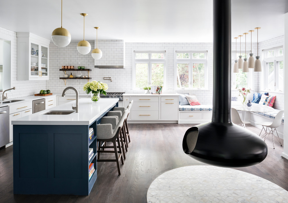 Inspiration for a large classic l-shaped kitchen/diner in New York with a double-bowl sink, shaker cabinets, blue cabinets, engineered stone countertops, white splashback, ceramic splashback, stainless steel appliances, medium hardwood flooring, an island and brown floors.
