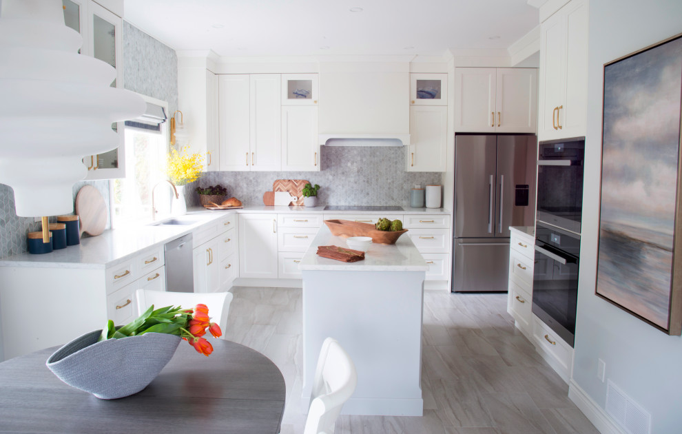 Large transitional u-shaped porcelain tile and gray floor kitchen photo in Vancouver with an undermount sink, shaker cabinets, white cabinets, quartz countertops, white backsplash, glass tile backsplash, stainless steel appliances, an island and white countertops