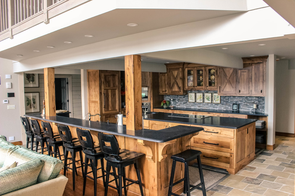Example of a mid-sized country galley limestone floor and multicolored floor eat-in kitchen design in Other with granite countertops, an island, an undermount sink, shaker cabinets, medium tone wood cabinets, gray backsplash, matchstick tile backsplash and stainless steel appliances