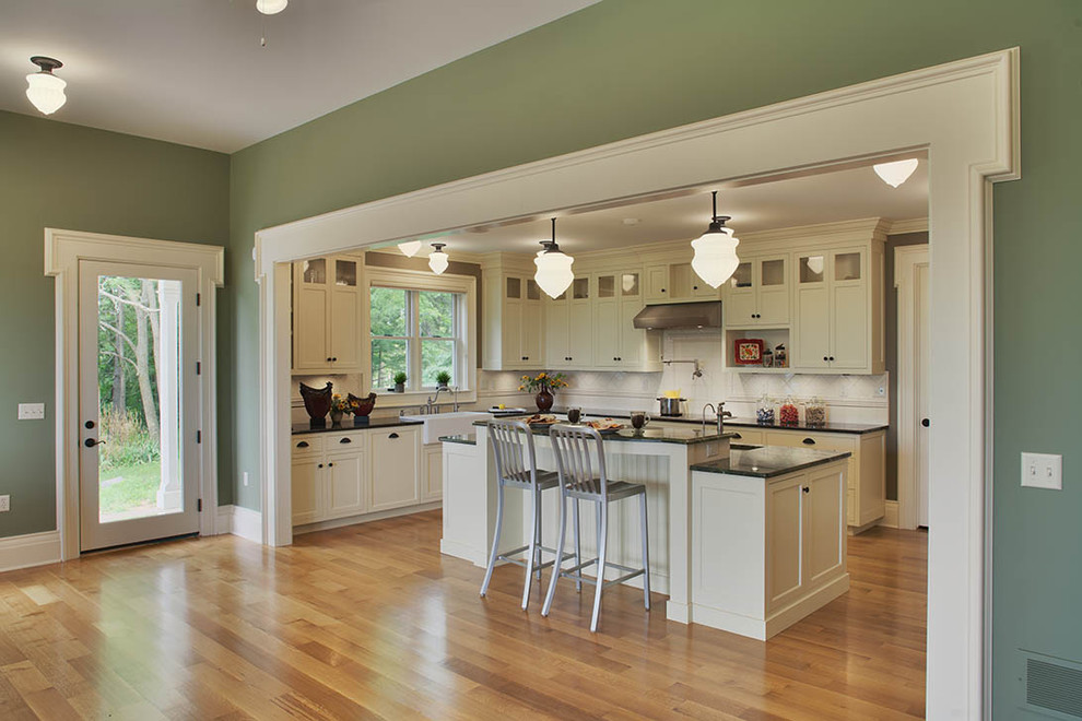 Bild på ett stort lantligt kök, med luckor med infälld panel, vita skåp, beige stänkskydd, en rustik diskho, granitbänkskiva, stänkskydd i keramik, integrerade vitvaror, mellanmörkt trägolv och en köksö