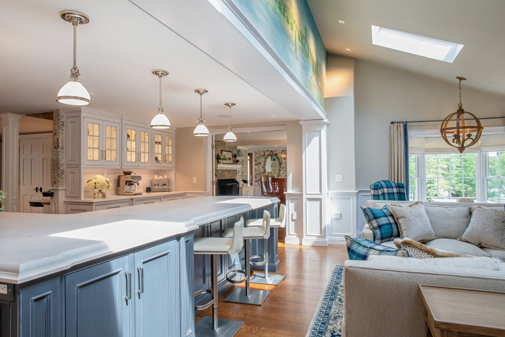 Bild på ett vintage vit vitt kök med öppen planlösning, med en rustik diskho, luckor med profilerade fronter, blå skåp, bänkskiva i kvarts, grått stänkskydd, stänkskydd i glaskakel, rostfria vitvaror, mellanmörkt trägolv, en köksö och brunt golv