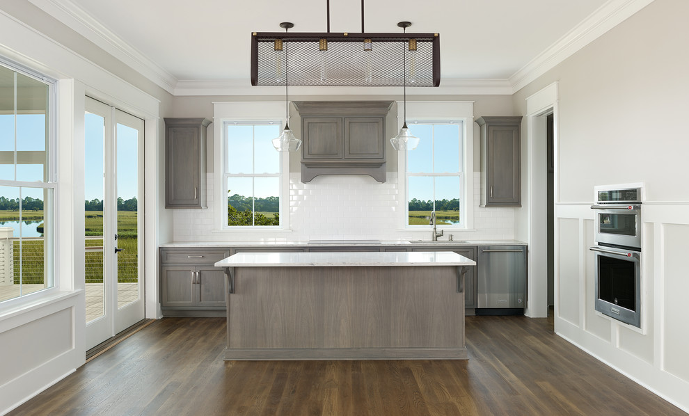 Design ideas for a classic kitchen in Charleston with a built-in sink, shaker cabinets, distressed cabinets, engineered stone countertops, white splashback, ceramic splashback, stainless steel appliances, medium hardwood flooring, an island, brown floors and white worktops.