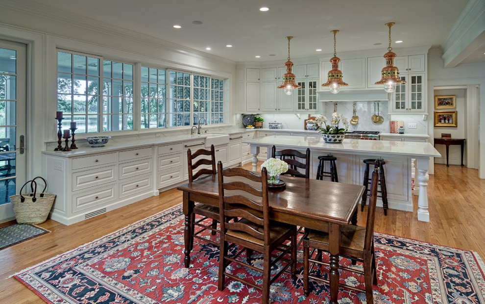 Exempel på ett stort klassiskt vit vitt u-kök, med en rustik diskho, luckor med upphöjd panel, vita skåp, bänkskiva i kvartsit, vitt stänkskydd, integrerade vitvaror, mellanmörkt trägolv och brunt golv