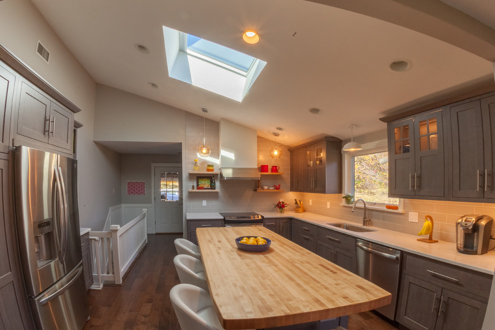 Inspiration for a mid-sized contemporary u-shaped dark wood floor enclosed kitchen remodel in Philadelphia with an undermount sink, shaker cabinets, gray cabinets, solid surface countertops, gray backsplash, subway tile backsplash, stainless steel appliances and an island