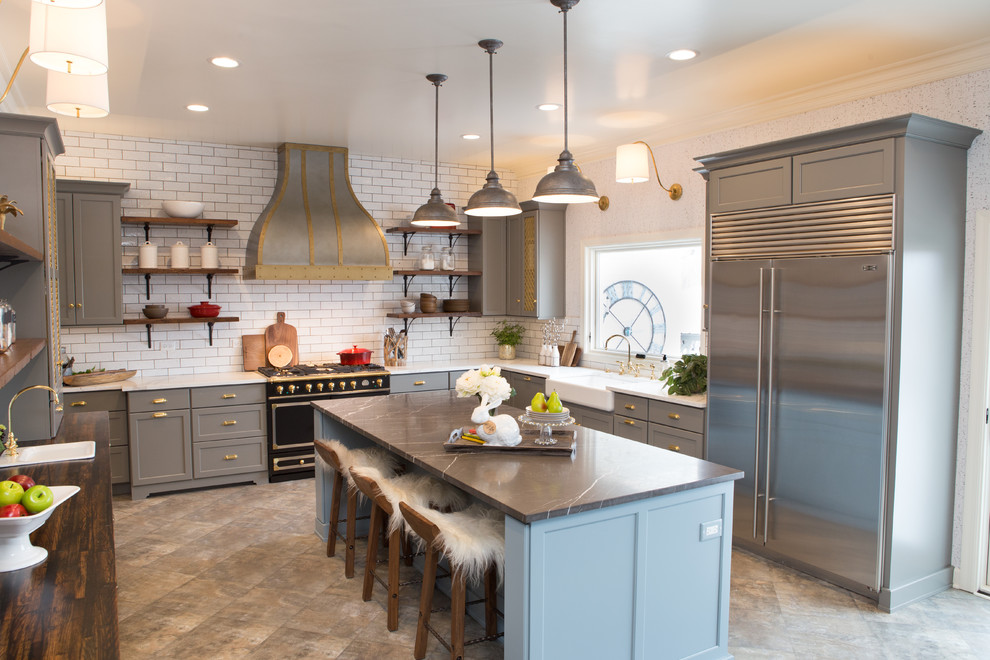 Example of a large transitional u-shaped porcelain tile and gray floor eat-in kitchen design in Chicago with a farmhouse sink, shaker cabinets, gray cabinets, limestone countertops, white backsplash, subway tile backsplash, black appliances and an island