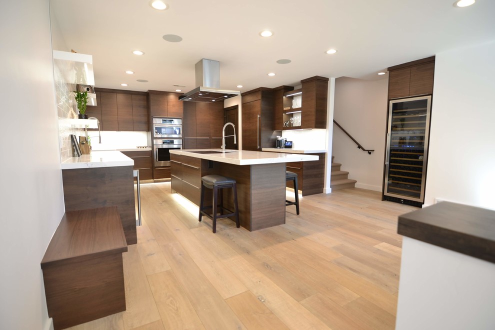Large trendy u-shaped light wood floor and brown floor eat-in kitchen photo in Salt Lake City with a drop-in sink, flat-panel cabinets, dark wood cabinets, quartzite countertops, white backsplash, stainless steel appliances, an island and white countertops