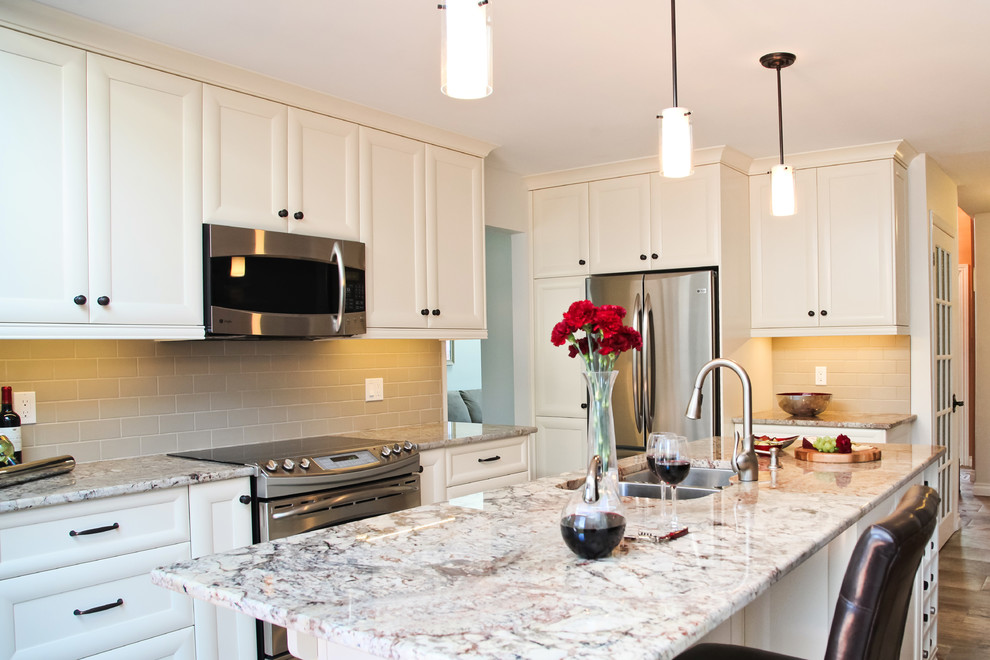 Example of a mid-sized transitional l-shaped porcelain tile eat-in kitchen design in Toronto with a double-bowl sink, recessed-panel cabinets, white cabinets, granite countertops, beige backsplash, subway tile backsplash, stainless steel appliances and an island