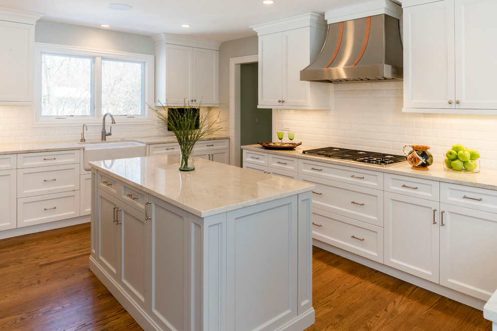 Eat-in kitchen - large transitional medium tone wood floor eat-in kitchen idea in Chicago with a farmhouse sink, shaker cabinets, white cabinets, quartzite countertops, white backsplash, ceramic backsplash, stainless steel appliances and an island