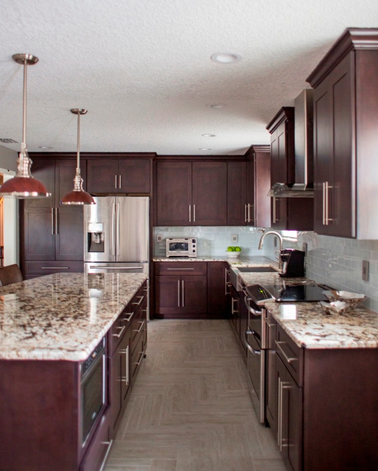 Inspiration for a large transitional l-shaped porcelain tile and beige floor eat-in kitchen remodel in Jacksonville with flat-panel cabinets, dark wood cabinets, granite countertops, white backsplash, stainless steel appliances and an island